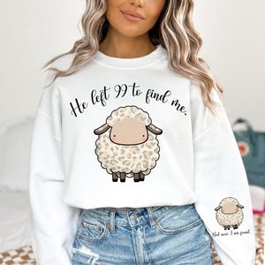 K&ouml;nnte beinhalten: Wei&szlig;er Pullover mit einem niedlichen Comic-Schaf und dem Text "He left 99 to find me." Das Schaf hat ein braunes Gesicht und ein Leopardenmuster. Der Text ist in Schwarz.