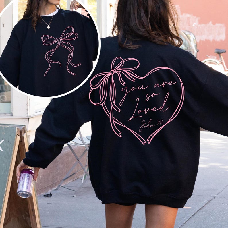 May include: Black sweatshirt with a pink ribbon bow on the front and a pink heart with the text "you are so loved John 3:16" on the back.