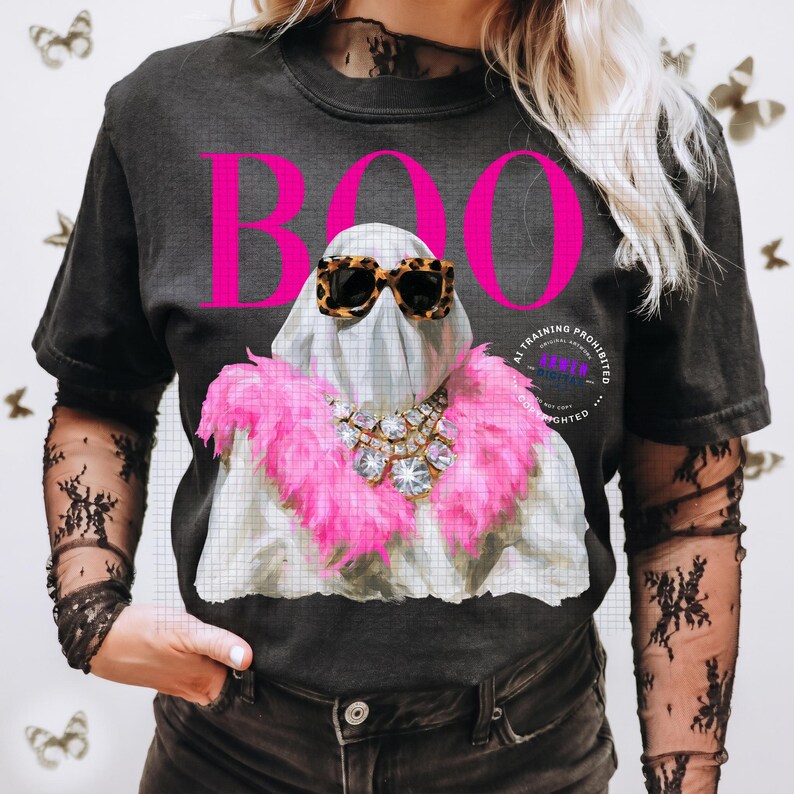 May include: A black short-sleeve t-shirt featuring a graphic of a white ghost wearing leopard print sunglasses and a bright pink feather boa with a large crystal necklace. The word BOO is printed in large hot pink letters above the ghost graphic.