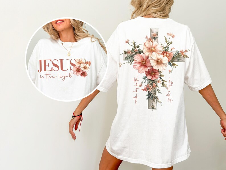 May include: White t-shirt with a floral cross design on the back and the text "Jesus is the light" with floral accents on the front. The text "walk by faith" is written on the cross.