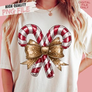 Puede incluir: Camiseta color crema con un dise&ntilde;o festivo de dos bastones de caramelo cruzados con rayas rojas y blancas, acentuados por un lazo dorado con purpurina. Las palabras "HIGH QUALITY PNG FILE" est&aacute;n impresas en la parte superior izquierda y "DIGITAL FILE ONLY" en la superior derecha.