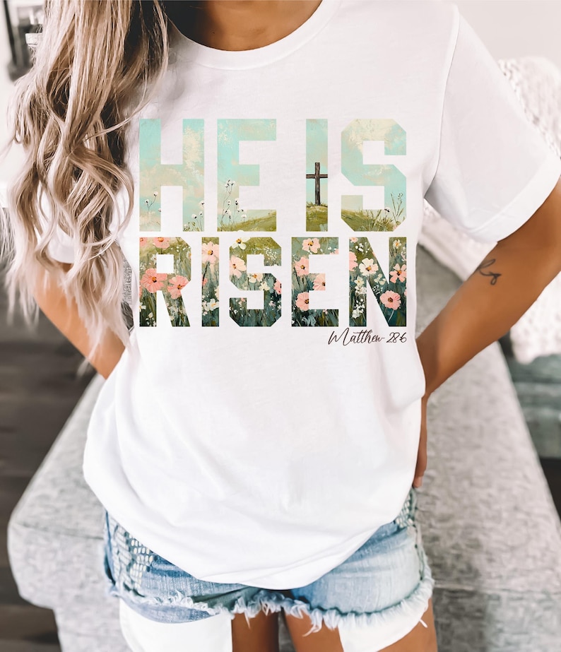 May include: White t-shirt with a floral design that spells out "He is Risen" with a cross and the text "Matthew 28:6".