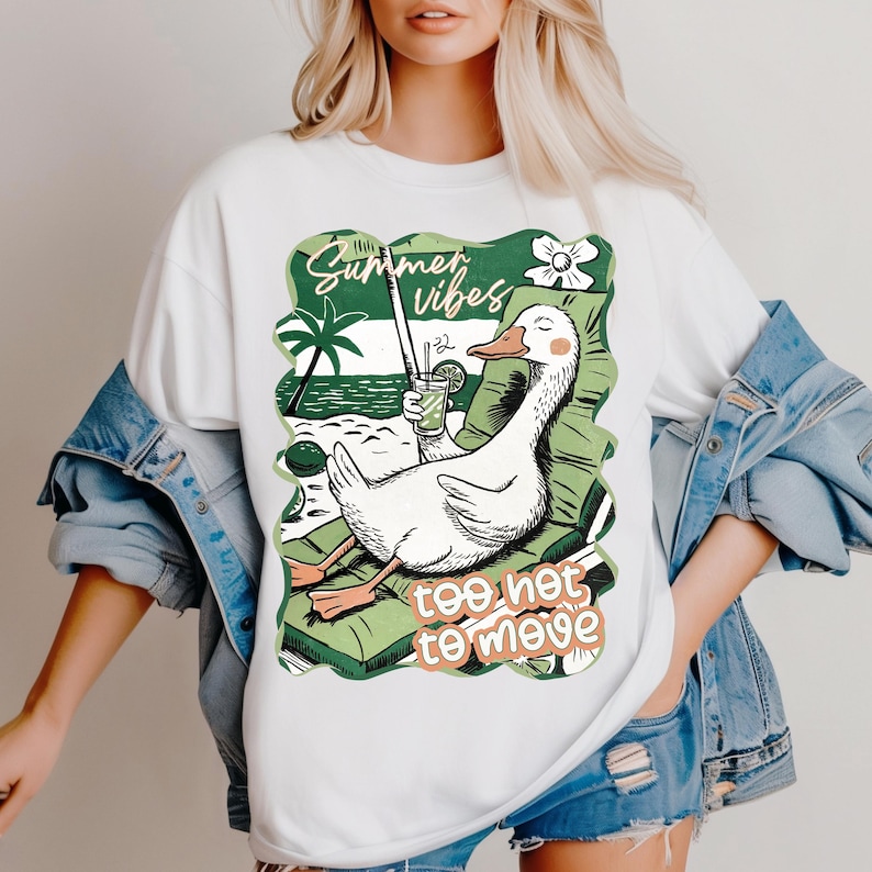Pu&ograve; includere: Maglietta bianca con una grafica di un'oca di cartone animato che indossa occhiali da sole e tiene un drink tropicale. L'oca &egrave; seduta su una sedia da spiaggia sotto una palma. Il testo "Summer vibes too hot to move" &egrave; stampato sulla maglietta.