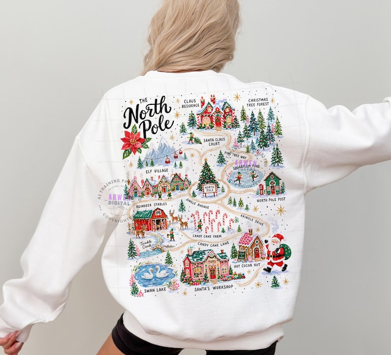 May include: A white long-sleeve sweatshirt featuring a colorful graphic map of the North Pole on the back. The illustration includes labels for Claus Residence, Elf Village, Reindeer Stables, Candy Cane Farm, and Santa's Workshop with Santa.