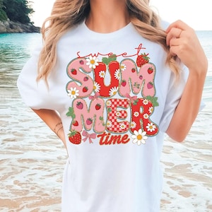 Pu&ograve; includere: Maglietta bianca con un design grafico rosa e rosso che dice "sweet summer time" con fragole e margherite.