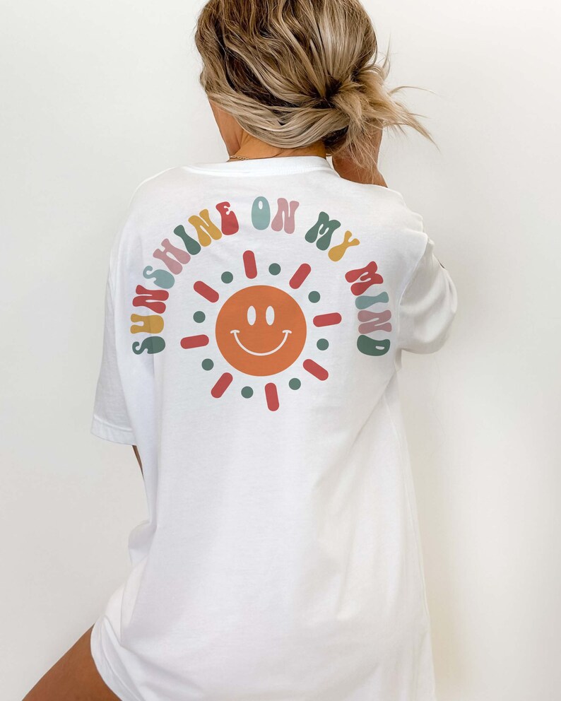 May include: White t-shirt with a colorful graphic of a smiling sun and the text "Sunshine on my mind".