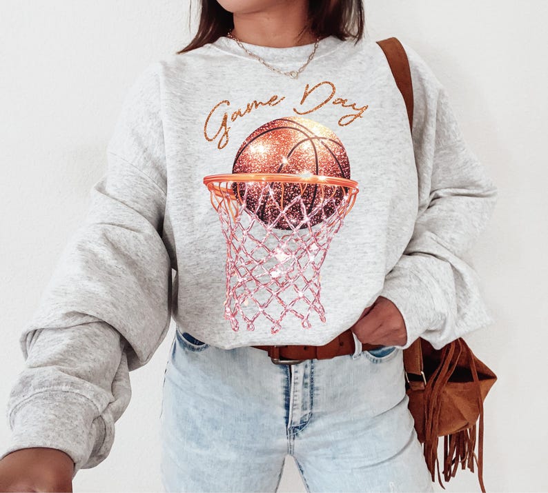 May include: A gray sweatshirt with the text "Game Day" and a glittery orange basketball in a pink net.