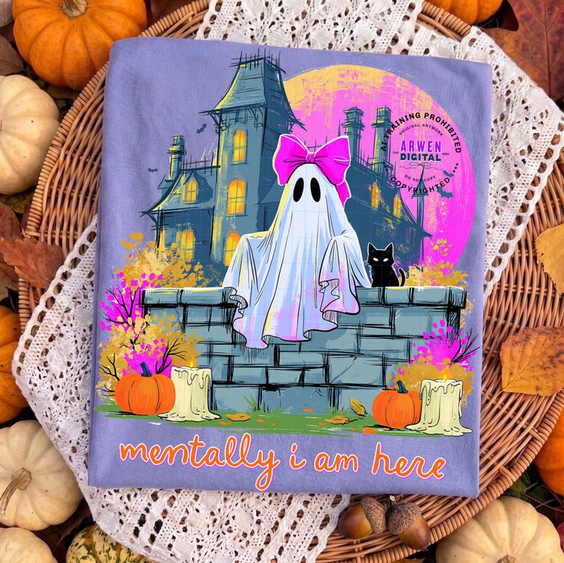 Puede incluir: Una camiseta de color morado claro con un gr&aacute;fico de un fantasma blanco con un lazo rosa brillante, un gato negro, una casa encantada y calabazas. El texto "mentally i am here" est&aacute; impreso en naranja, con un logo "ARWEN DIGITAL".