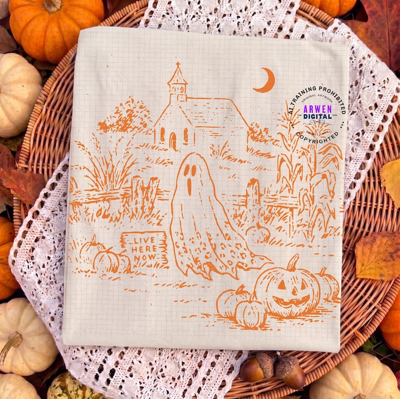 May include: A cream-colored fabric square featuring an orange line-art illustration of a ghost, a church, pumpkins, and a sign that reads "LIVE HERE NOW". The design includes a crescent moon and corn stalks, all set against a subtle grid pattern.