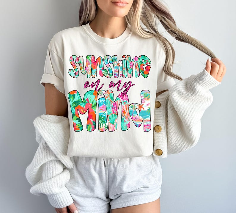 Pu&ograve; includere: Maglietta bianca con una grafica floreale che dice "Sunshine on my mind".