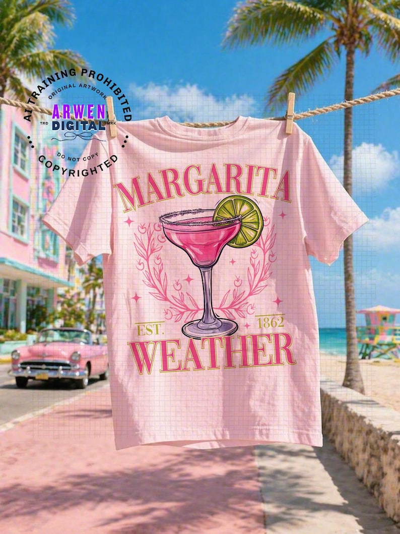 May include: A light pink t-shirt with a margarita design. The design includes a pink cocktail in a stemmed glass with a lime slice, surrounded by a floral wreath. The text "MARGARITA WEATHER" is printed on the shirt.