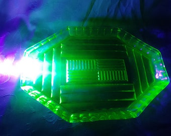 May include: A green glass dish with a geometric design. The dish is octagonal and has a raised center section with a repeating pattern of lines.