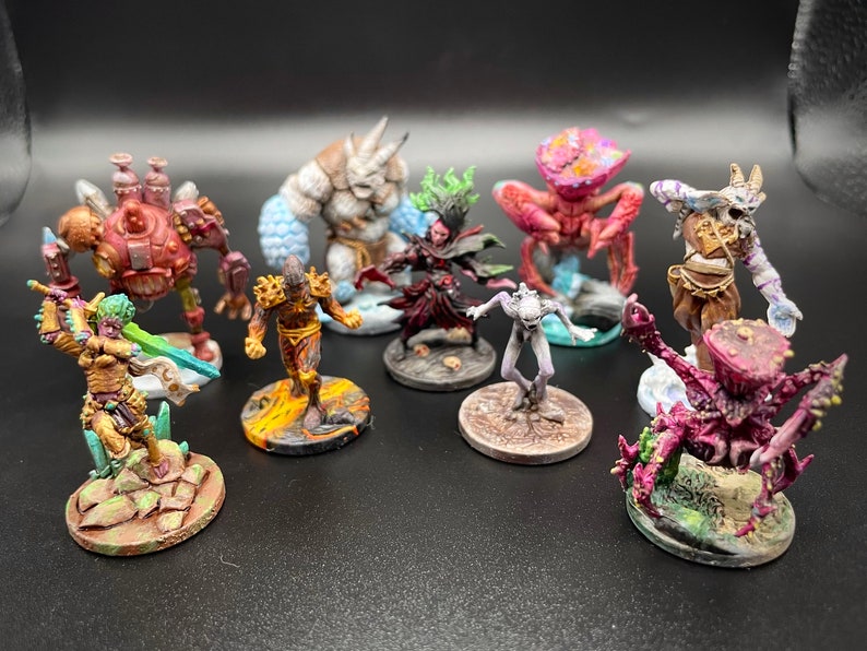 May include: A collection of eight hand-painted miniature figures, each on a circular base. The figures include a humanoid with a sword, a creature with a large head, a creature with a crab-like body, a humanoid with a staff, a humanoid with a horned helmet, a humanoid with a large head, a humanoid with a staff, and a creature with a large head.