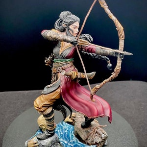 May include: A painted miniature figurine of a female elf archer, standing on a rocky base with water flowing around her feet. She is wearing a red and gold outfit and holding a bow and arrow.