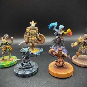 May include: Six painted miniature figures on circular bases. The figures are a green-skinned warrior with a sword, a blue-skinned figure with a staff, a brown-skinned figure with a shield, a green-skinned figure with a sword, a brown-skinned figure with a staff, and a brown-skinned figure with a sword.