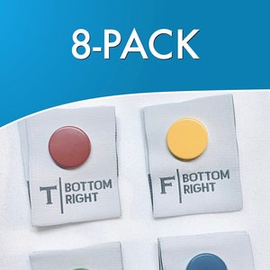 Peut inclure: Lot de huit étiquettes en tissu avec des cercles de différentes couleurs et le texte "BOTTOM RIGHT" imprimé sur chaque étiquette. Les étiquettes sont blanches avec du texte gris.