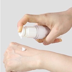 Puede incluir: Una botella de pl&aacute;stico blanca con una bomba y un cuerpo transparente que dispensa una crema blanca en la mano de una persona.