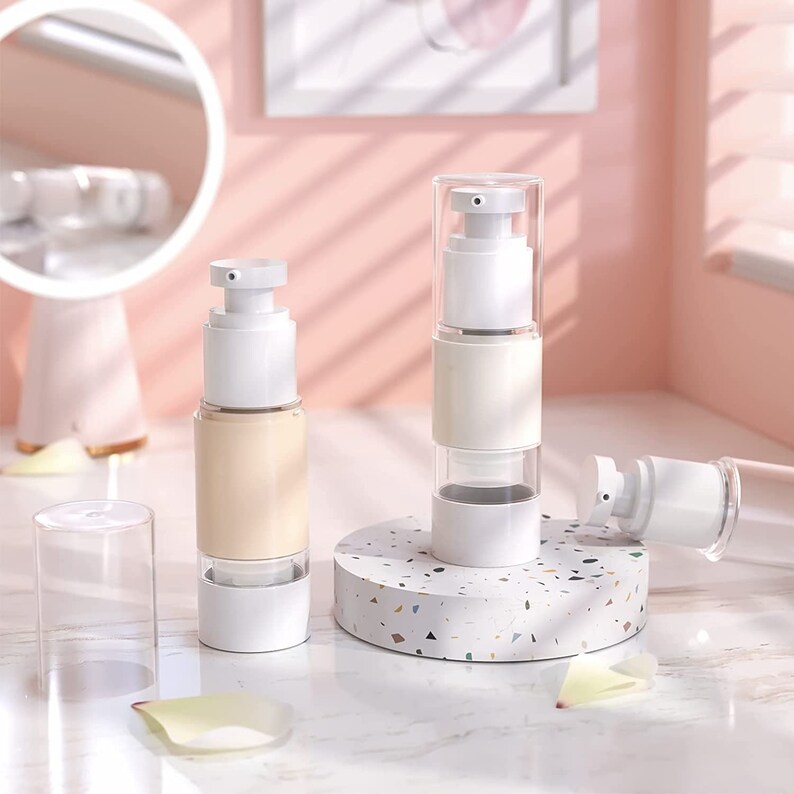 Puede incluir: Tres botellas de pl&aacute;stico blanco y transparente con bomba, con base blanca y parte superior transparente. Las botellas est&aacute;n sobre una superficie de terrazo blanco y gris.