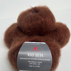 May include: A skein of brown Kid Seta yarn, a blend of 70% mohair and 30% silk. The label reads "Kid Seta Mischung mit feinstem Super-Kid Mohair 70% Mohair / mohair 30% Seide / silk 25g ca. 210m".