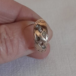 Op de afbeelding: Een gouden ring met een decoratief ontwerp en kleine stenen die in de band zijn gezet.