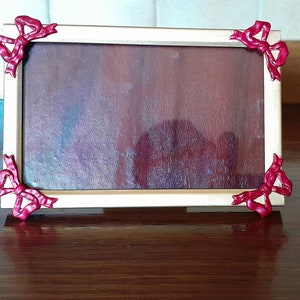 Liten återvunnen fotoram, målad guld med mörk rubinröda rosetter.
