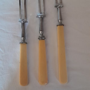 Puede incluir: Tres tenedores de servir de plata con mangos de color marfil. Los tenedores tienen dos dientes cada uno.