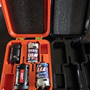 May include: Two orange and black cases with foam inserts for storing small motors. The cases are open and show the motors inside. The motors are labelled "Titan 12T 1550" and "R1".