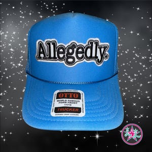 May include: A blue trucker hat with a black and white embroidered patch that says "Allegedly." The hat has a black mesh back and a white label with the text "OTTO WORLD FAMOUS FOAM FRONT OSFM TRUCKER DURABLE SNAP CLOSURE."
