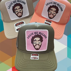 May include: Three trucker hats in beige, peach, and olive green. Each hat features a square patch with the text "LEAVE ME MALONE" above a cartoon face. The hats have a mesh back and a curved brim.