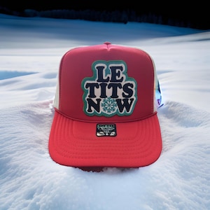 May include: Red and white trucker hat with a green and black patch that says "Le Tits Now" with a snowflake in the middle.