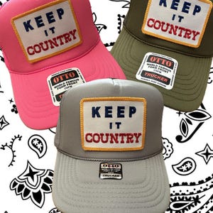 May include: Three trucker hats with a mesh back and a front panel featuring a yellow and red embroidered patch that says "Keep It Country". The hats are in pink, gray, and green.