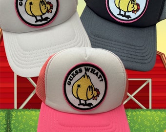 May include: Three trucker hats with a pink, white, and gray mesh back. Each hat features a yellow chicken with the text "Guess What?" in a pink circle.