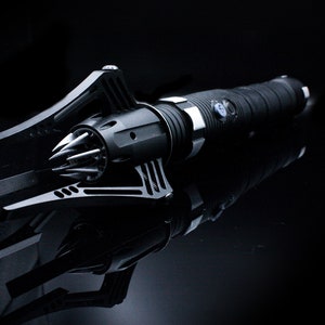 May include: A black metal weapon with a spiked head and a textured handle. The weapon is lying on a black surface.