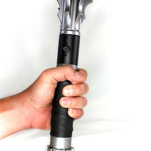 May include: A silver and black handheld weapon with a spiked head and a textured black grip.