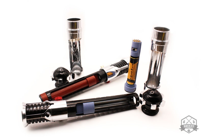 May include: A disassembled lightsaber with a black and silver handle, a red and brown middle section, and a silver and blue tip. The lightsaber is in pieces, with the handle, middle section, and tip separated. There are also two silver lightsaber hilt extensions.