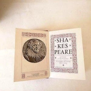 Peut inclure: Un livre vintage avec une couverture rouge et blanche. La couverture avant présente un portrait de William Shakespeare dans un cadre rond. Le titre du livre est "SHAKESPEARE" dans une police décorative.