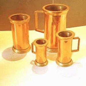 Peut inclure: Un ensemble de quatre récipients cylindriques en cuivre aux finitions métalliques. Une grande carafe est dotée d'une poignée latérale, tandis que deux tasses plus petites possèdent également des poignées. Le quatrième récipient est un cylindre simple.