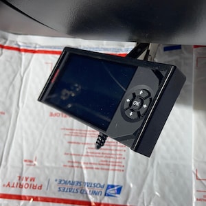 May include: A black device with a small screen and a circular control panel with buttons labeled "OK", "up", "down", "left", and "right".