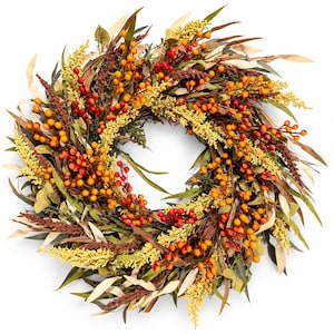 Puede incluir: Una corona circular con un arreglo denso de follaje artificial, que incluye hojas largas y delgadas de color verde y bronceado, racimos de tallos plumosos de color amarillo brillante y numerosas bayas pequeñas y redondas en rojo, naranja y amarillo.