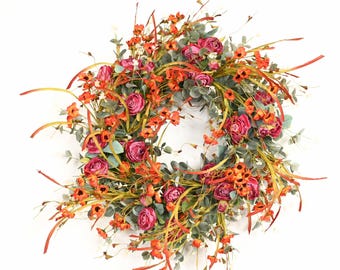 May include: A circular wreath featuring deep magenta peony-like flowers, small orange blossoms, and muted green eucalyptus leaves interspersed with thin, wispy golden-brown grass-like stems. The number 26154 is printed in black in the bottom right corner.