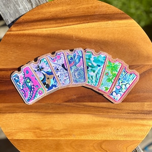 May include: Seven colorful fabric card holders with a gold trim. The card holders feature various patterns and designs, including paisley, floral, and geometric prints.