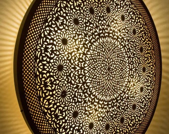 May include: A round, decorative ceiling light fixture with a intricate, laser-cut metal design. The light fixture is made of a dark brown metal and has a circular shape.