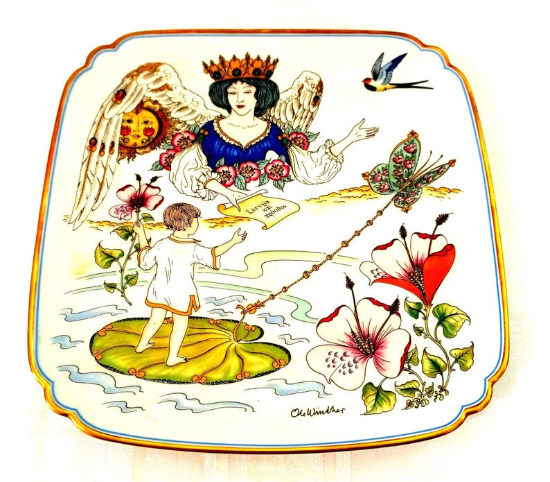 May include: A square decorative porcelain plate with a gold-trimmed edge featuring a colorful illustration of a winged figure wearing a crown, a child standing on a lily pad, large hibiscus flowers, a butterfly, and a swallow with the text Eervia kai Agapes.