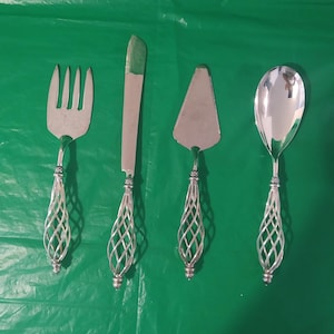 Könnte beinhalten: Set aus vier silbernen Servierbesteck mit komplizierten, geflochtenen Griffen. Das Set enthält einen Kuchenspachtel, ein Buttermesser, einen Servierlöffel und eine Gabel.