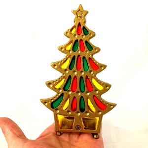 Könnte beinhalten: Goldfarbene Weihnachtsbaumdekoration mit roten, grünen und gelben Akzenten im Glasmalerei-Stil. Der Baum hat einen Stern oben und wird in einer Hand gehalten. Der Baum ist etwa 10 cm hoch.