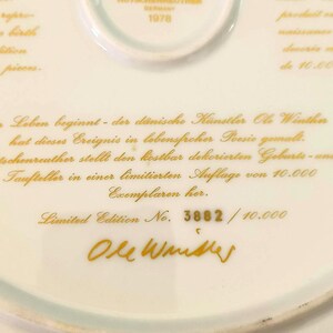May include: A white porcelain plate featuring gold text and a Hutschenreuther Germany 1978 stamp. The text includes the artist name Ole Winther, a German description, and the limited edition number 3882 out of 10,000. The plate has a smooth finish.