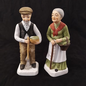 17cm Bisque Porcelain Figurines of a Gentleman Farmer and a Woman with a Basket and Cane. Made in Korea.