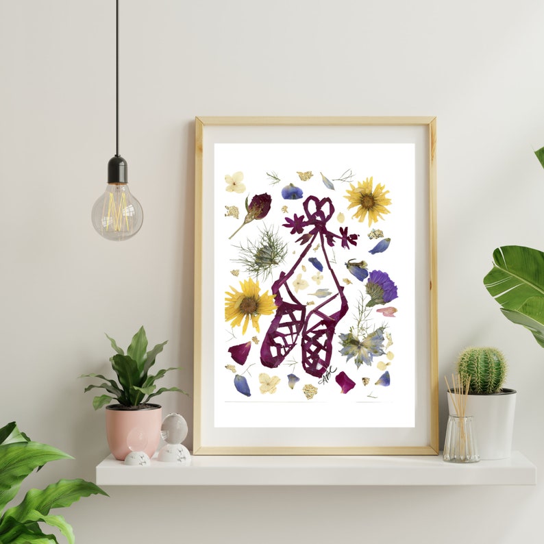 Puede incluir: Una impresi&oacute;n enmarcada de un par de zapatos de baile irland&eacute;s burdeos hechos con flores prensadas. Los zapatos est&aacute;n rodeados de una variedad de flores secas, incluyendo girasoles amarillos, nomeolvides azules y flores silvestres moradas.