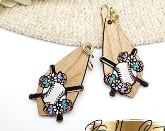 May include: A pair of wooden earrings with a baseball and floral design. The earrings are shaped like teardrops and have gold hooks. The baseball is surrounded by pink, purple, and blue flowers.