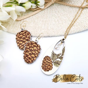 May include: A set of wooden earrings and a necklace featuring a pine cone design. The earrings are brown and gold with a detailed pine cone design. The necklace is a teardrop shape with a gold chain and a pine cone design with a gold leaf. The necklace also has a clear crystal accent.